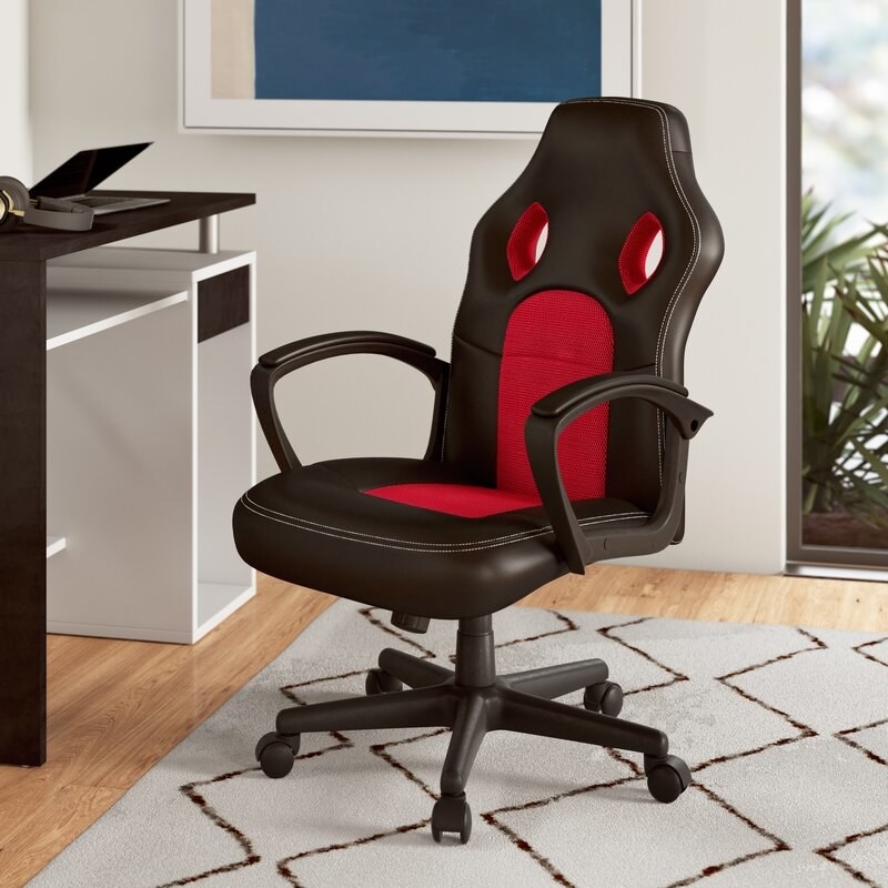A black and red gaming chair with a a high back that has two cut outs, rounded armrests, with a five star base with wheels