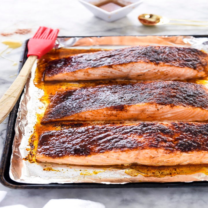 Three pieces of glazed salmon on a sheet pan, fresh from the oven.