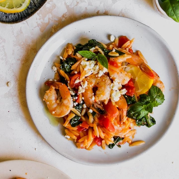 A plate of tomato-y orzo with shrimp and herbs .
