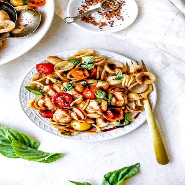 A plate of orecchiette, mozzarella, tomato, and basil tossed in balsamic.
