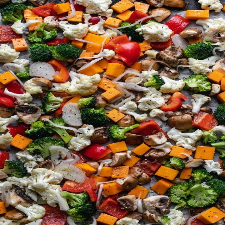 Vegetables (broccoli, mushrooms, sweet potato, peppers, and cauliflower) on a sheet pan.