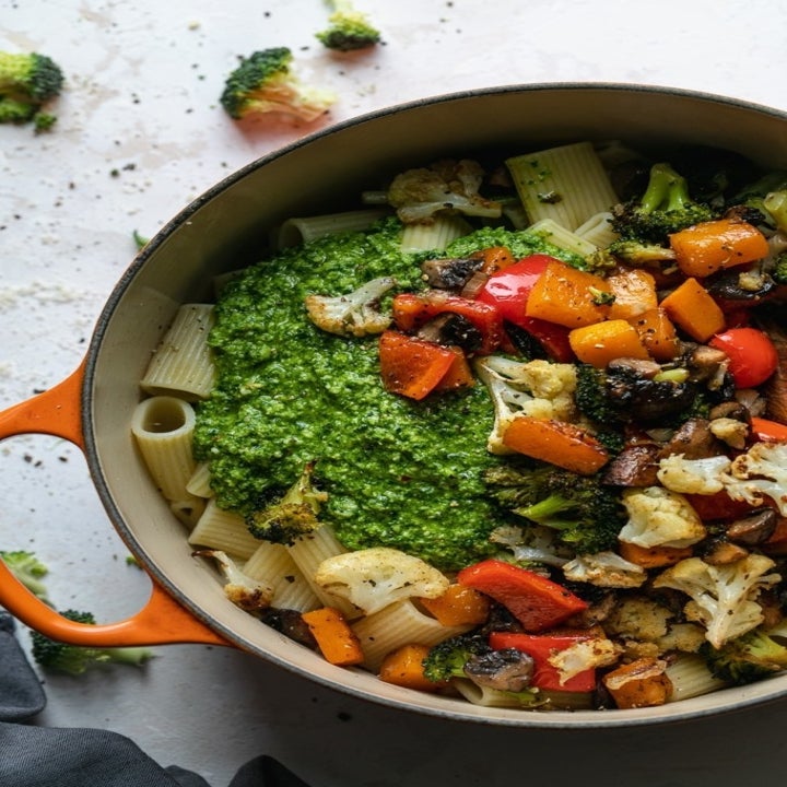 A sauce pan with cooked pasta, roasted vegetables, and lots of pesto.