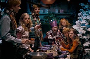 The entire Weasley family and Hermione standing around a table decorated for Christmas