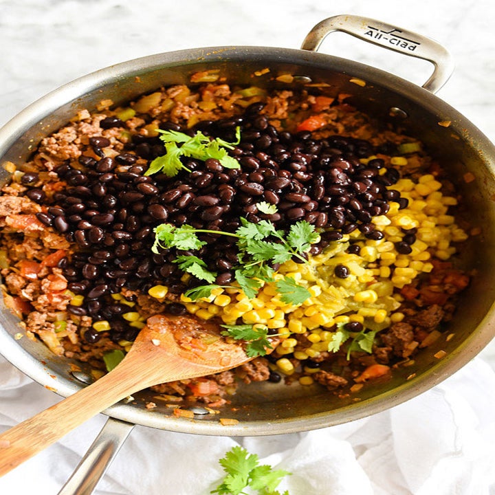 A big pot full of the stuffing ingredients: sausage, black beans, corn, diced tomatoes, and herbs.