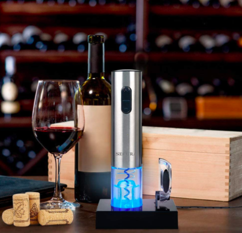 Silver electric wine opener next to a glass of red wine and brown corks