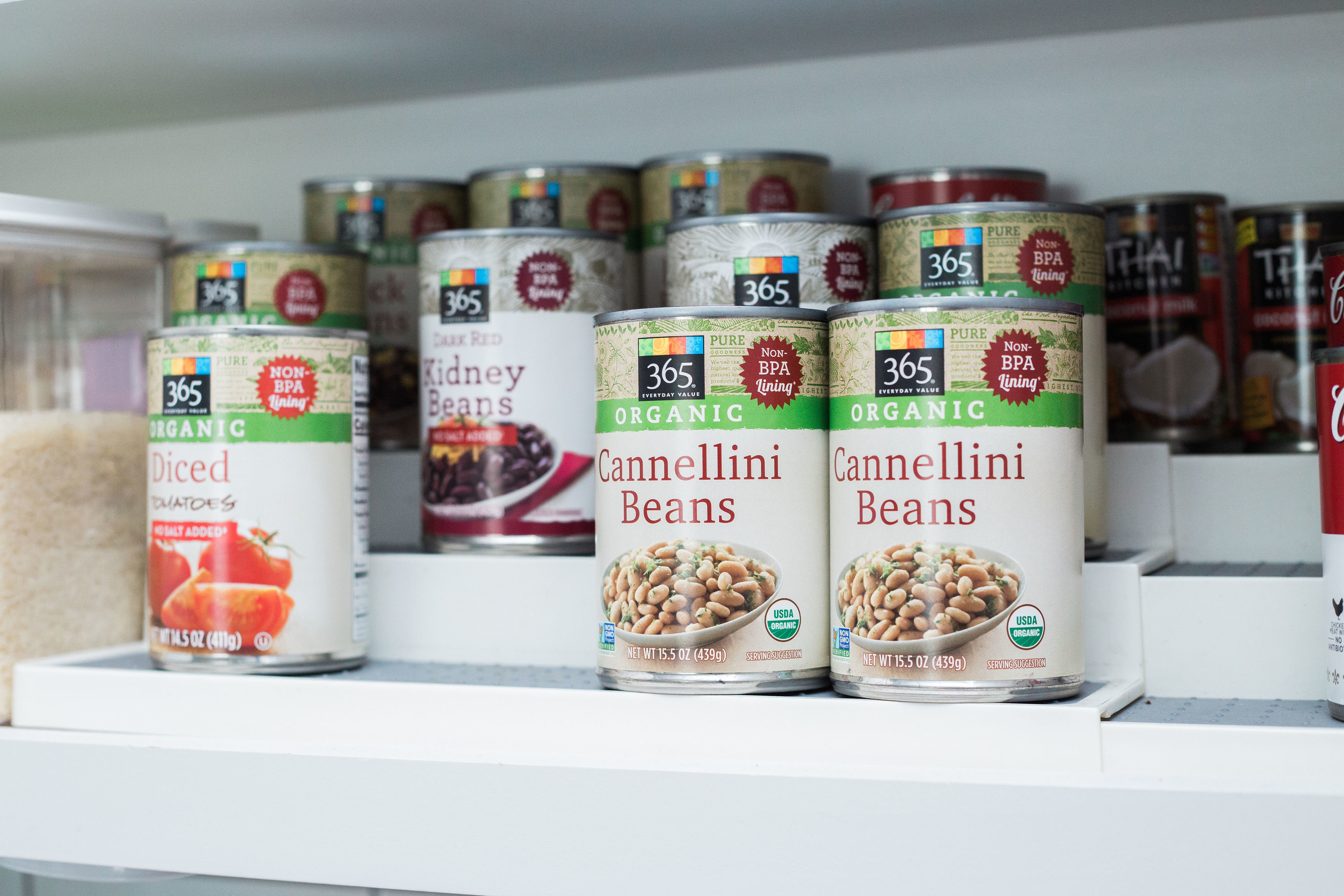 A collection of cans on a 3-tiered, expandable step shelf