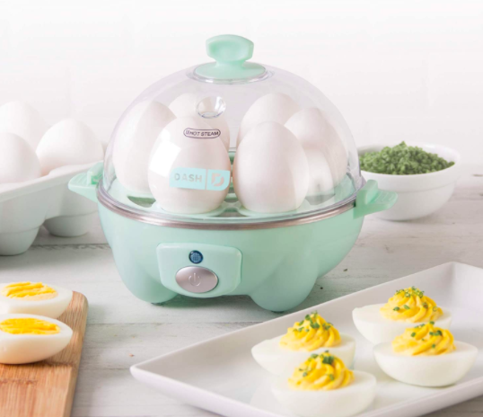 Light blue Dash Rapid Egg Cooker with six eggs inside next to a plate of deviled eggs