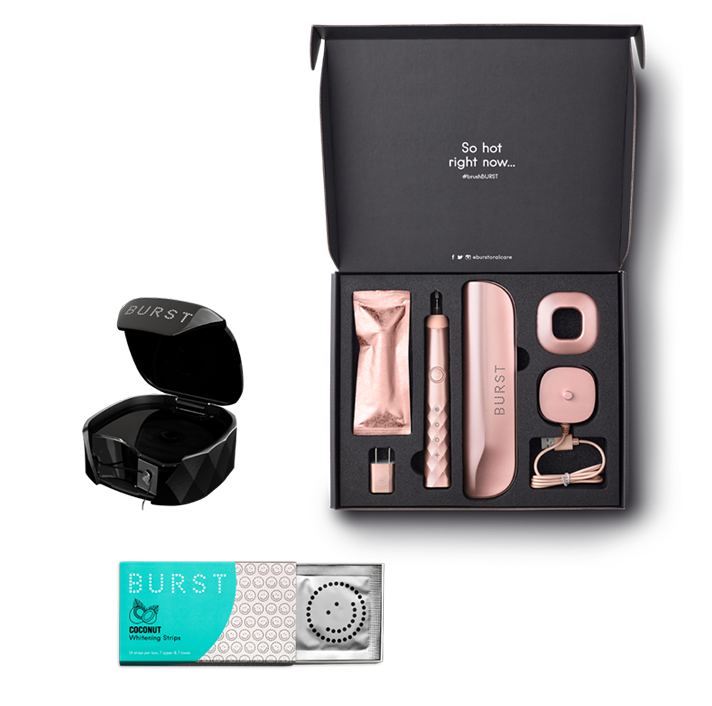 Open. black packaging with a rose-colored toothbrush and attachments, a black floss box, and a pack of tooth whiteners