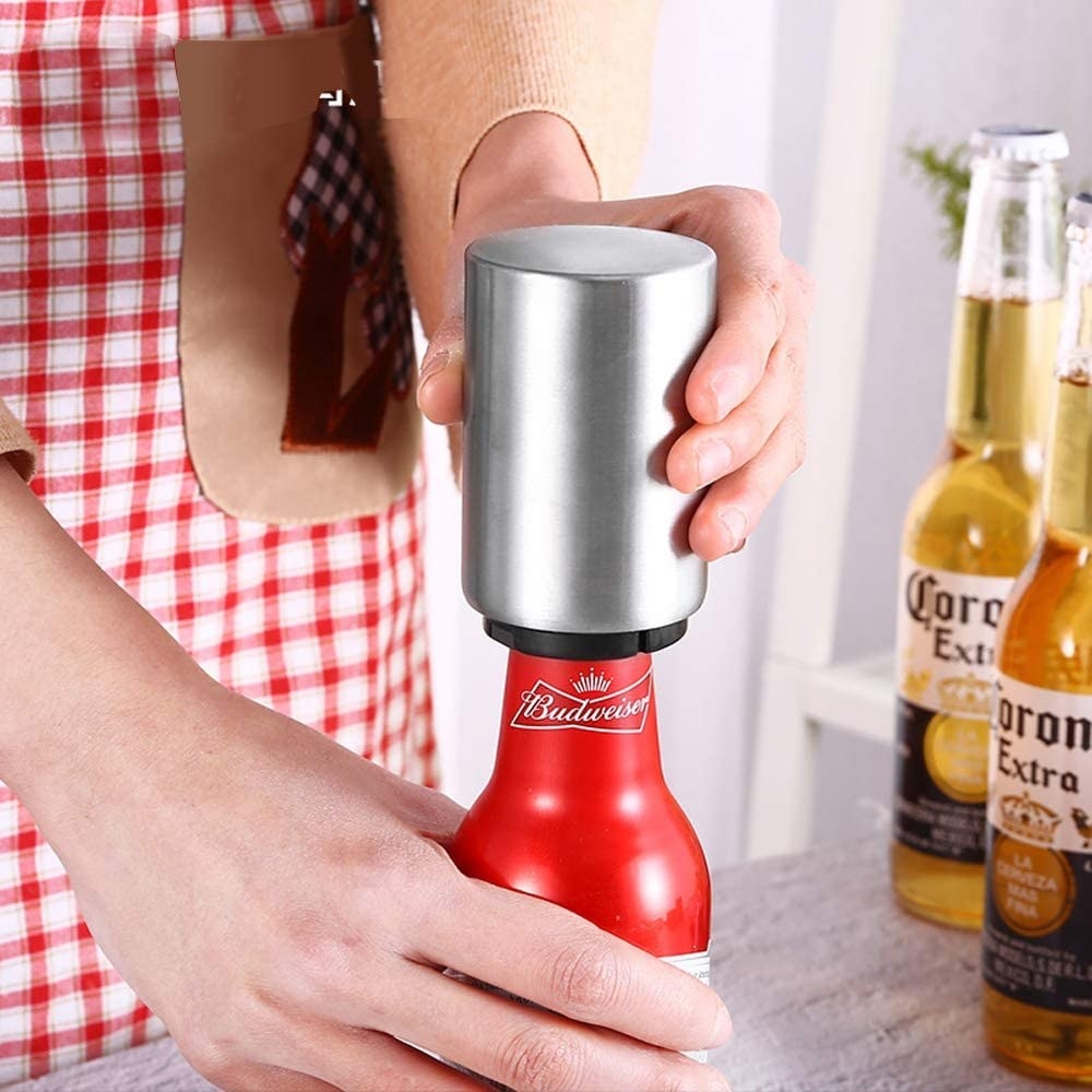 A person using the bottle opener to crack open a beer