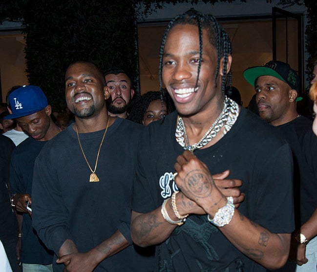 A candid shot of Kanye West and Travis Scott smiling at an industry event