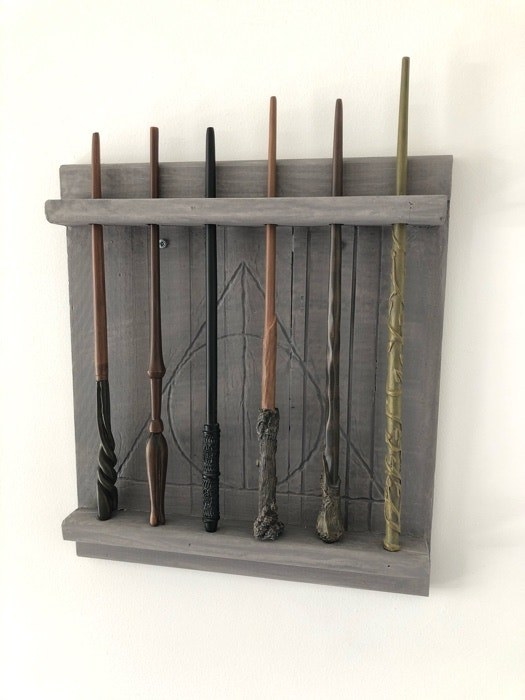 Wands on a wand shelf carved with the Deathly Hallows symbol
