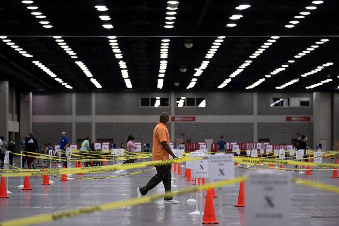A man walks through a maze of caution tape that has been set up to keep people at a safe distance from each other
