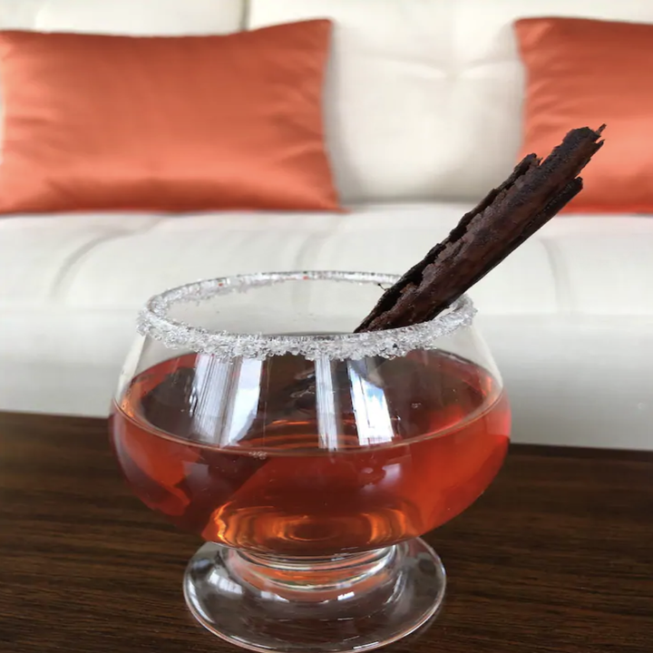 A squat glass holds a red, slightly transparent cocktail