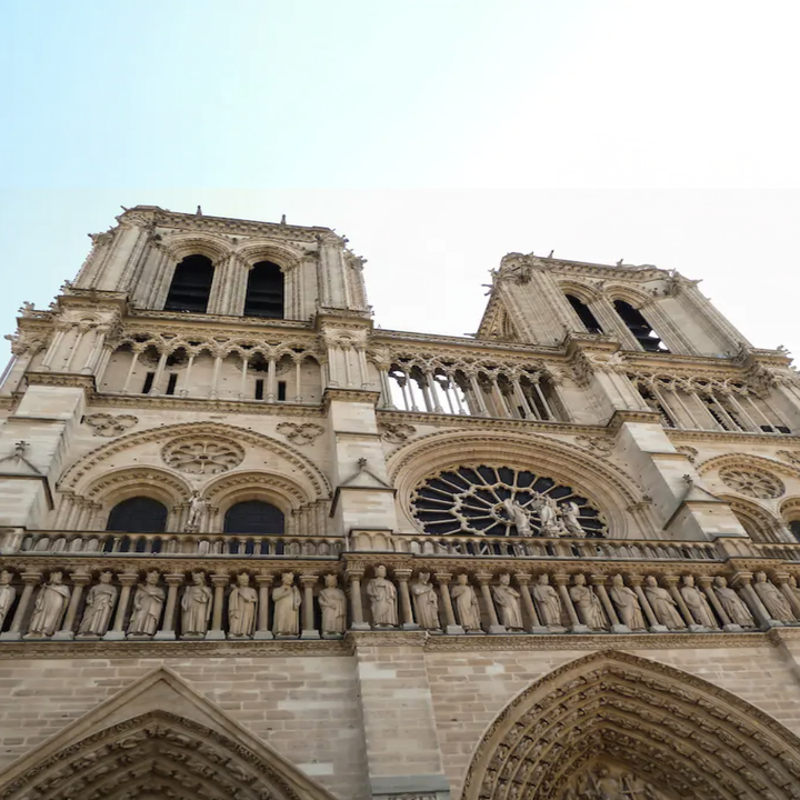 An upwards shot of the Notre Dame cathedral before a blue sky