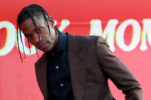 Travis Scott posing in a suit at a Hollywood event