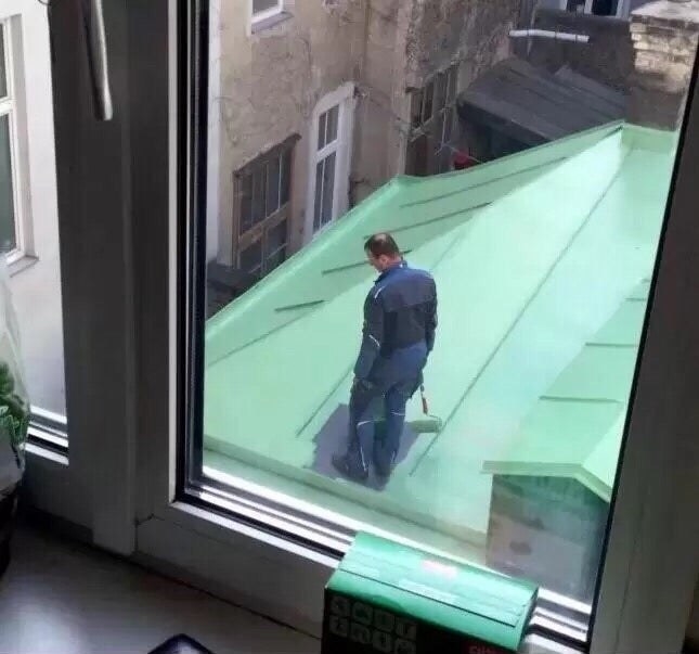 a man painting a roof is stuck in the middle of it