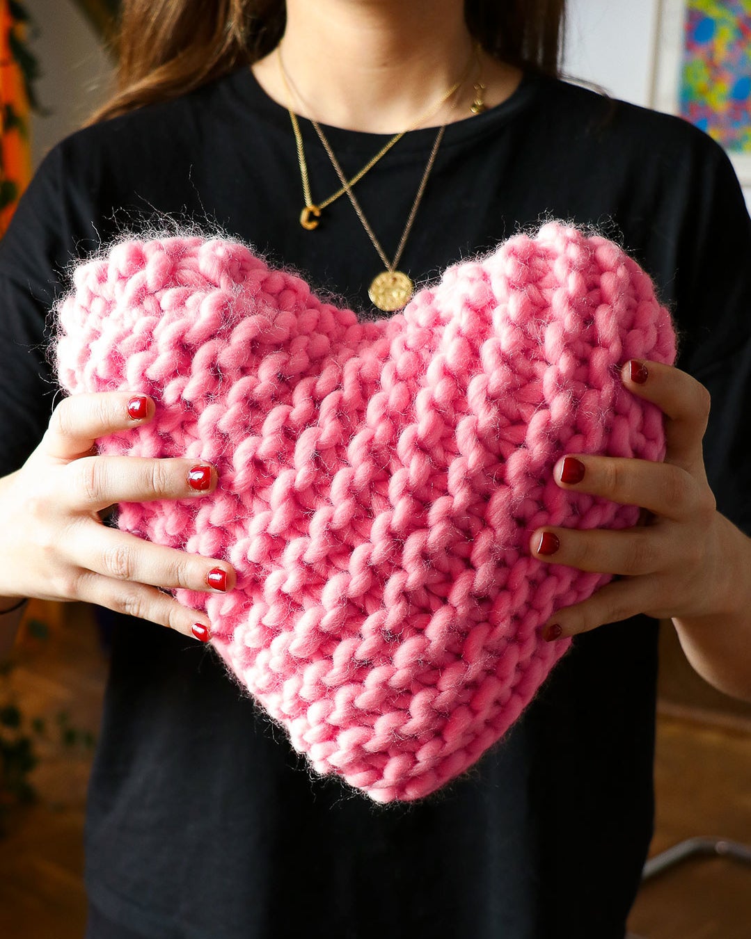 model holding small bright pink chunky knit pillow