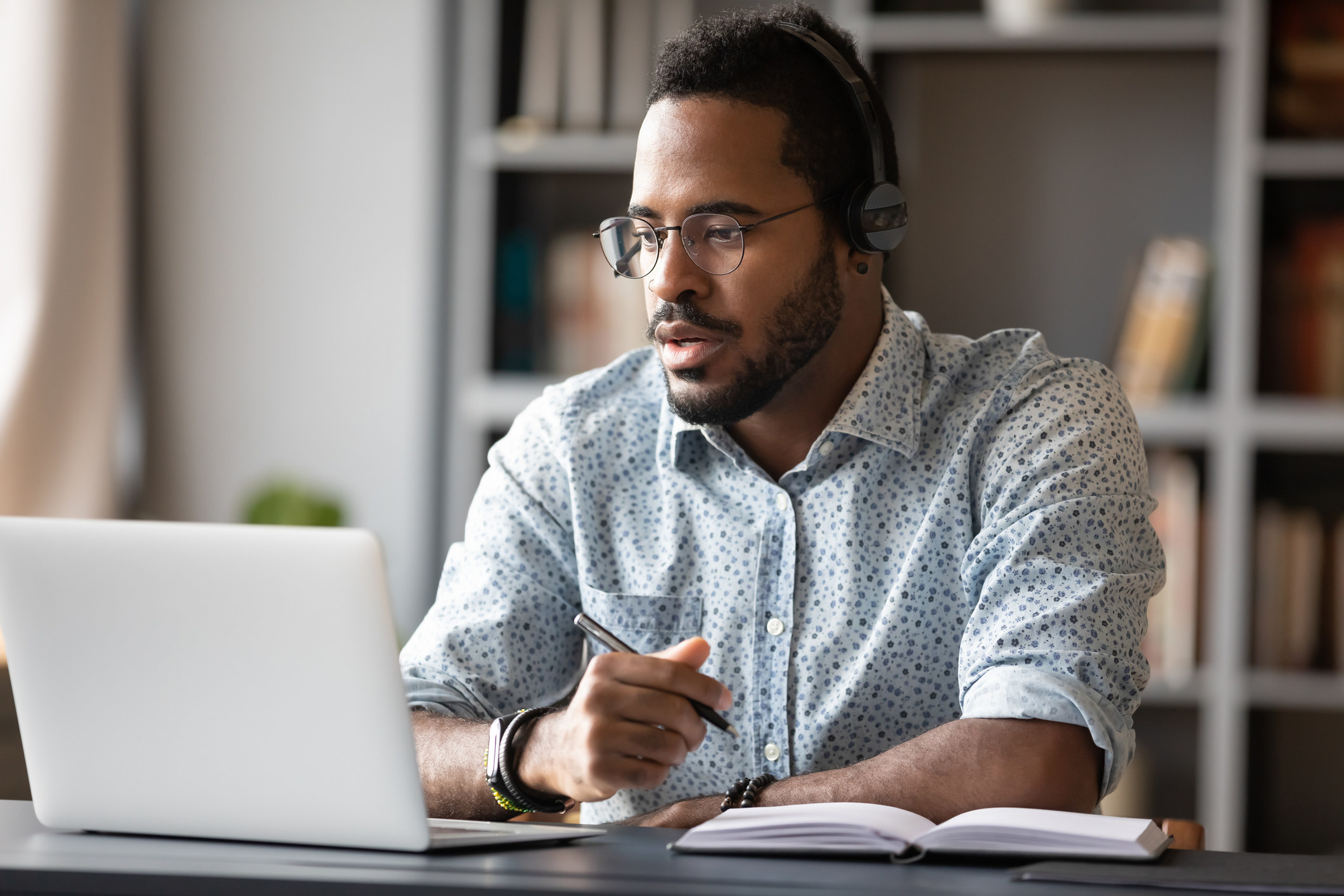 A focused student attends a virtual class with a laptop and headphones