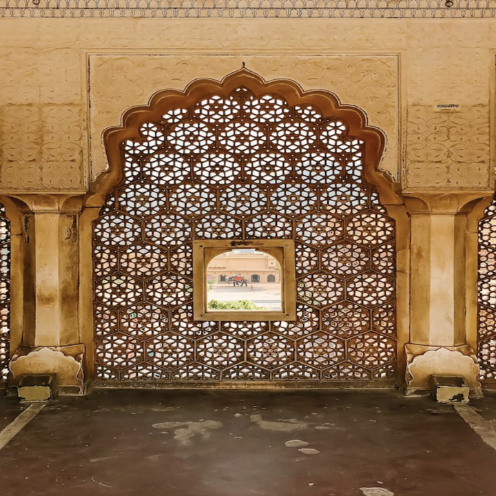 A photo of an intricately decorated outdoor window that resembles lace and is embedded in an archway