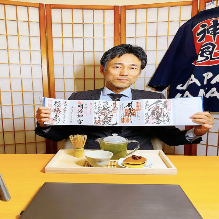 A man holds up a menu while sitting at a restaurant and a tray of tea in front of him