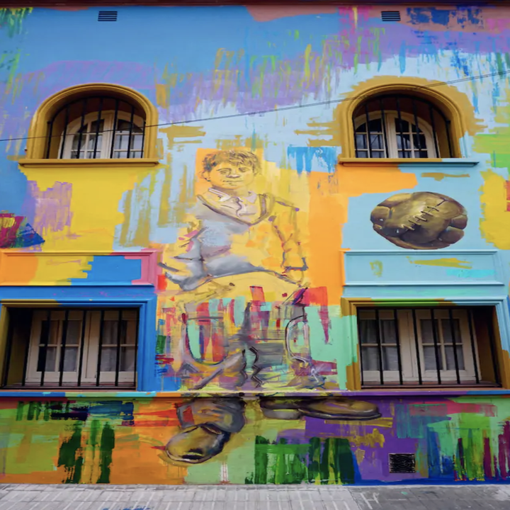 A building with barred windows is covered in graffiti in a multitude of bright colors