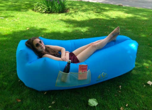 Reviewer lays down in blue inflatable lounger in their backyard