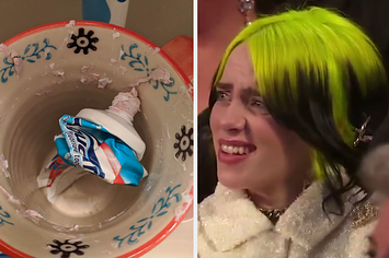 A cap-less bottle of toothpaste sitting a toothpaste smeared cup and Billie Eilish looking at it with disgust