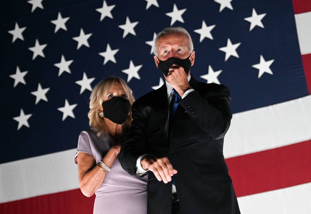 Joe and Jill Biden wear face masks, standing in front of an American flag