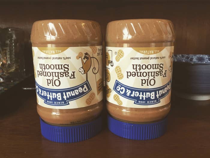 Two containers of peanut butter being stored upside down.