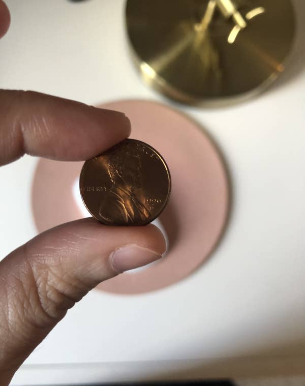 A penny being held in someone&#x27;s hand.