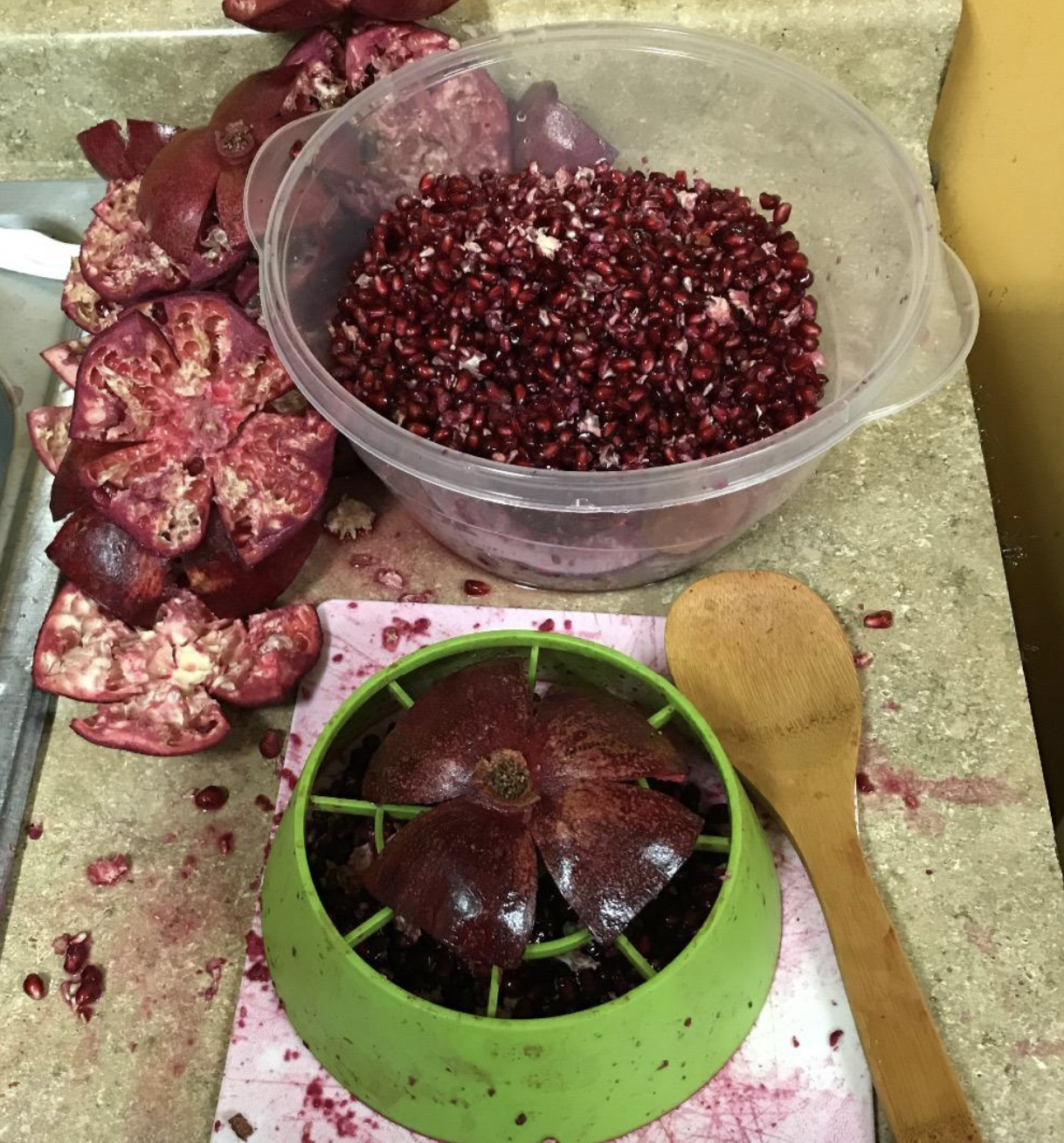 reviewer photo of green cutter, half open pomegranate, and container filled with seeds