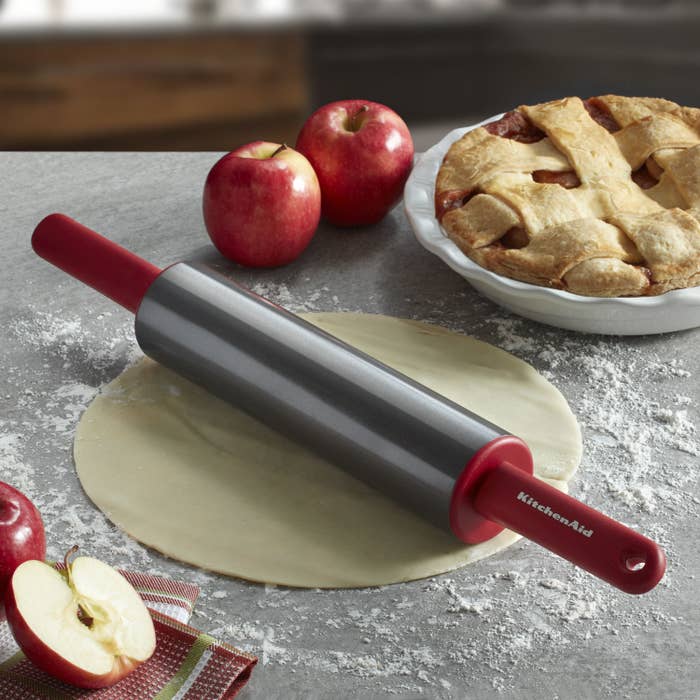 A metal rolling pin with red handles