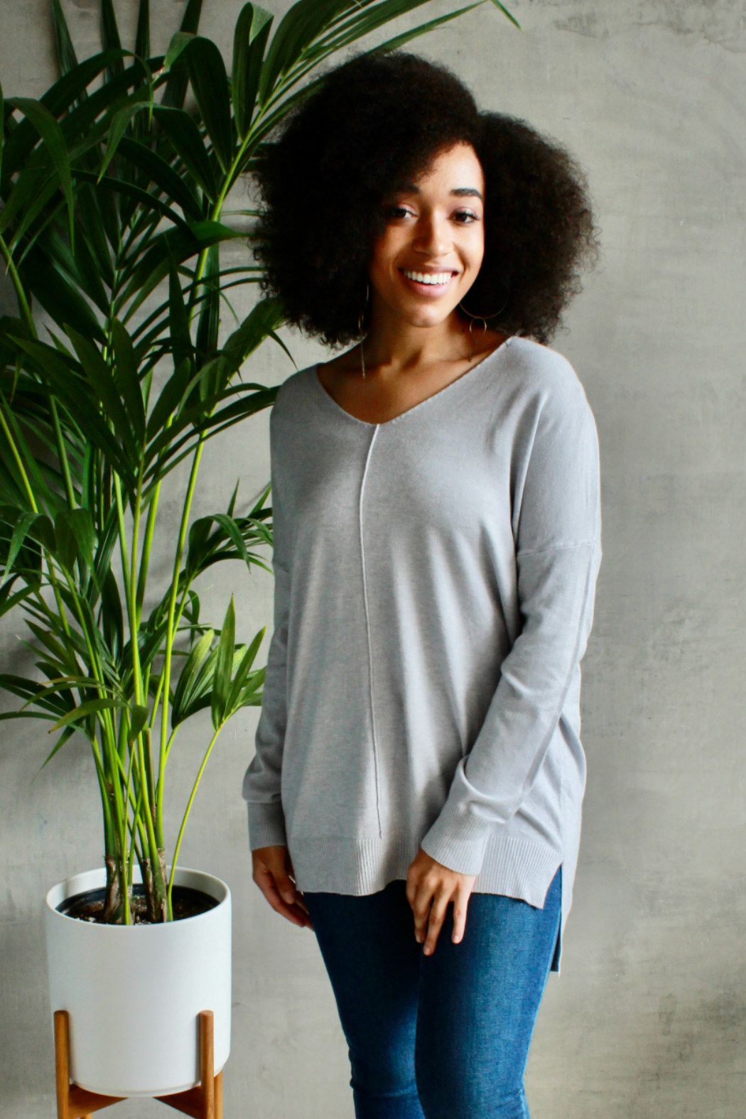 Model wearing the v-neck grey sweater with a seam down the front middle