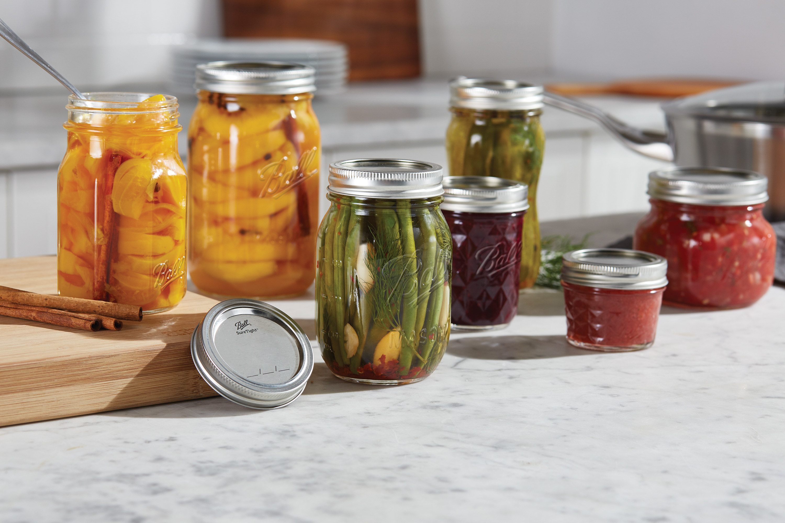 Canning jars with silver lids filled with fruits and vegetables