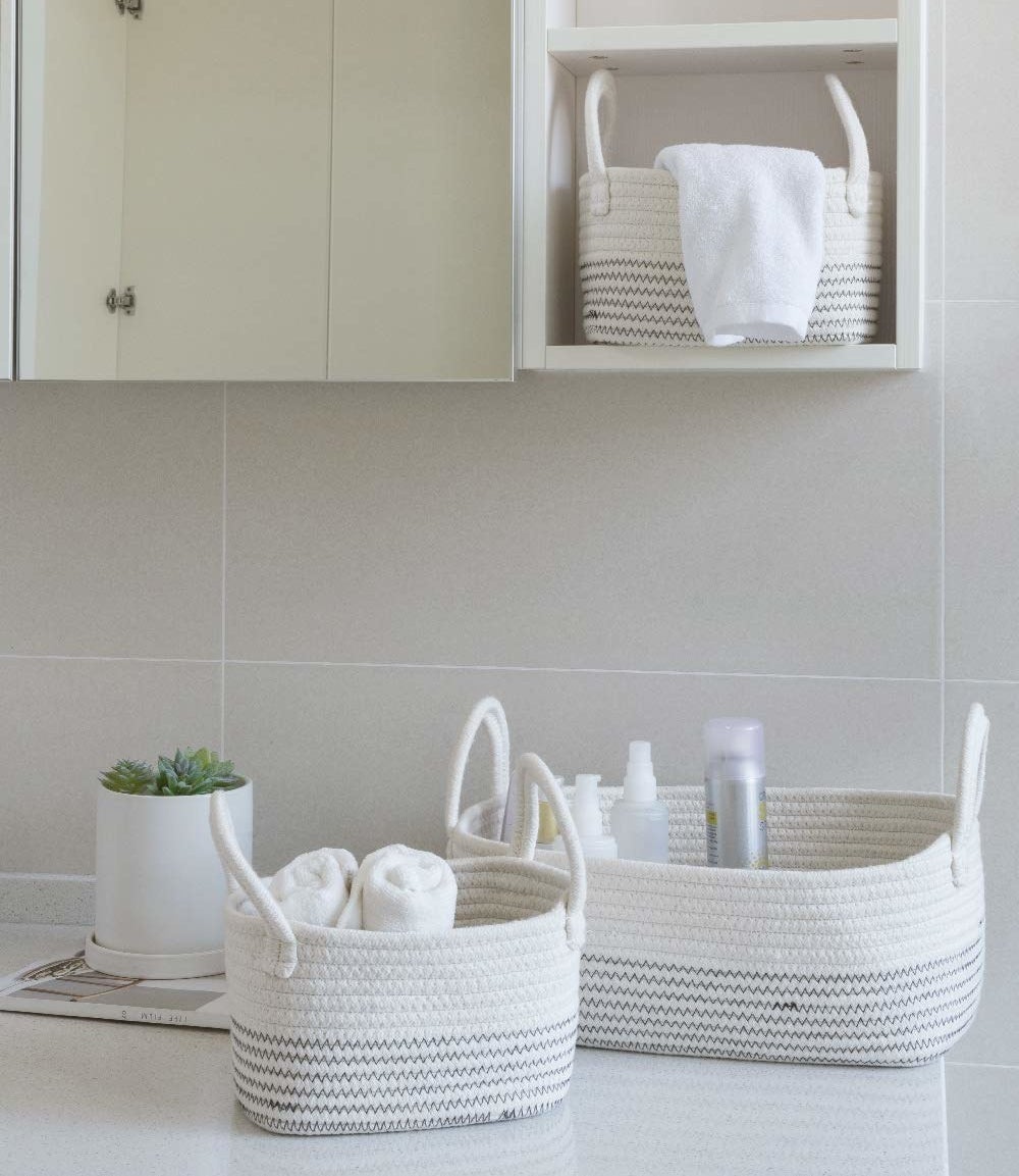 Three differently-sized woven baskets in white with grey zig-zag stripes around the bottom halves