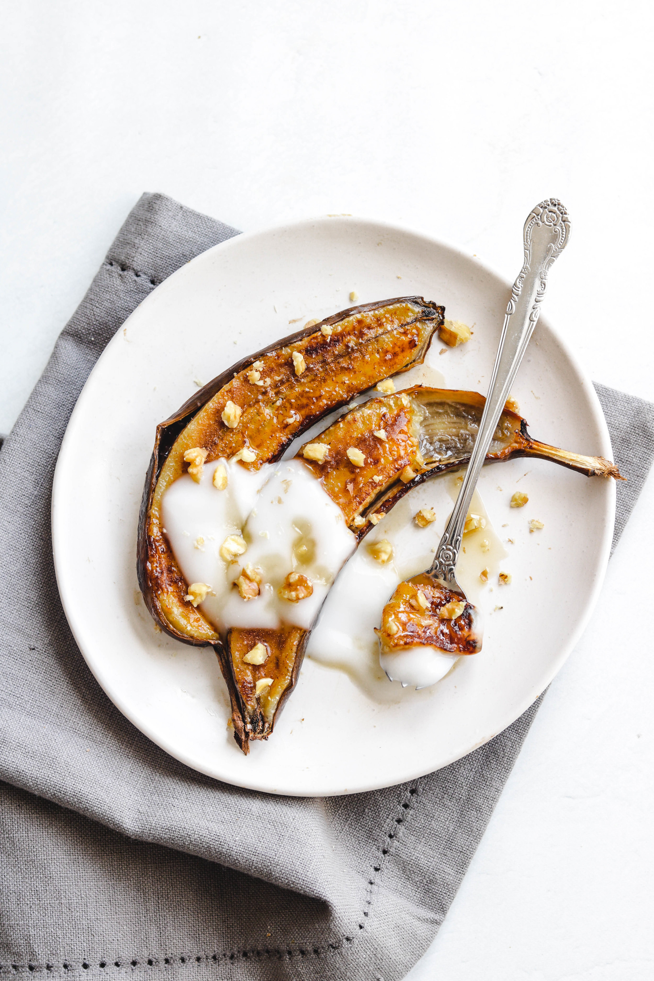 An air fried banana sliced in half and topped with yogurt and chopped nuts.