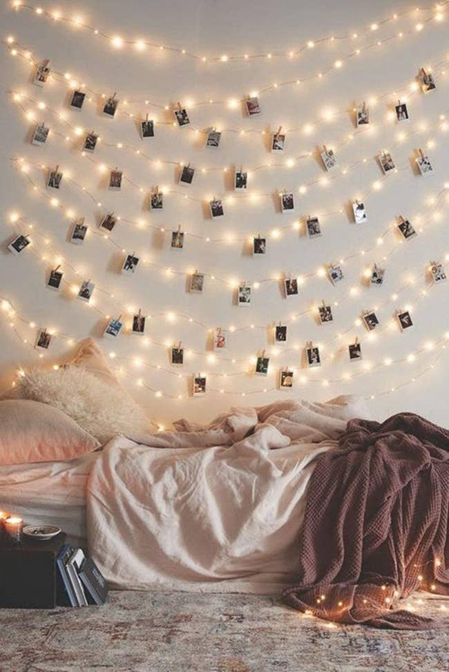string lights with polaroid pics clipped onto them above a bed