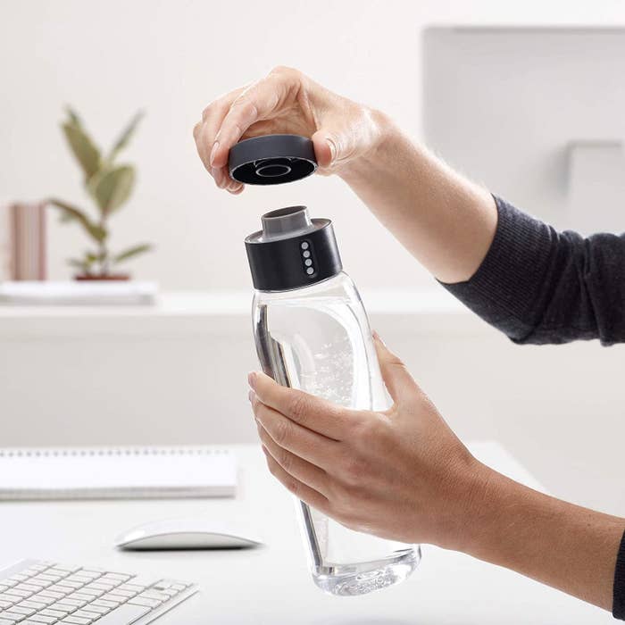 model holding clear water bottle with black cap