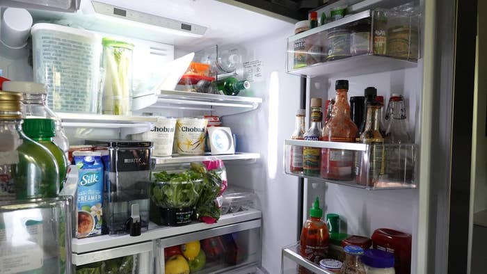 A fridge packed with condiments, fruits, vegetables, dairy, and containers