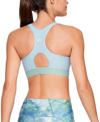a model showing the keyhole cut out in the back of the sports bra in light blue