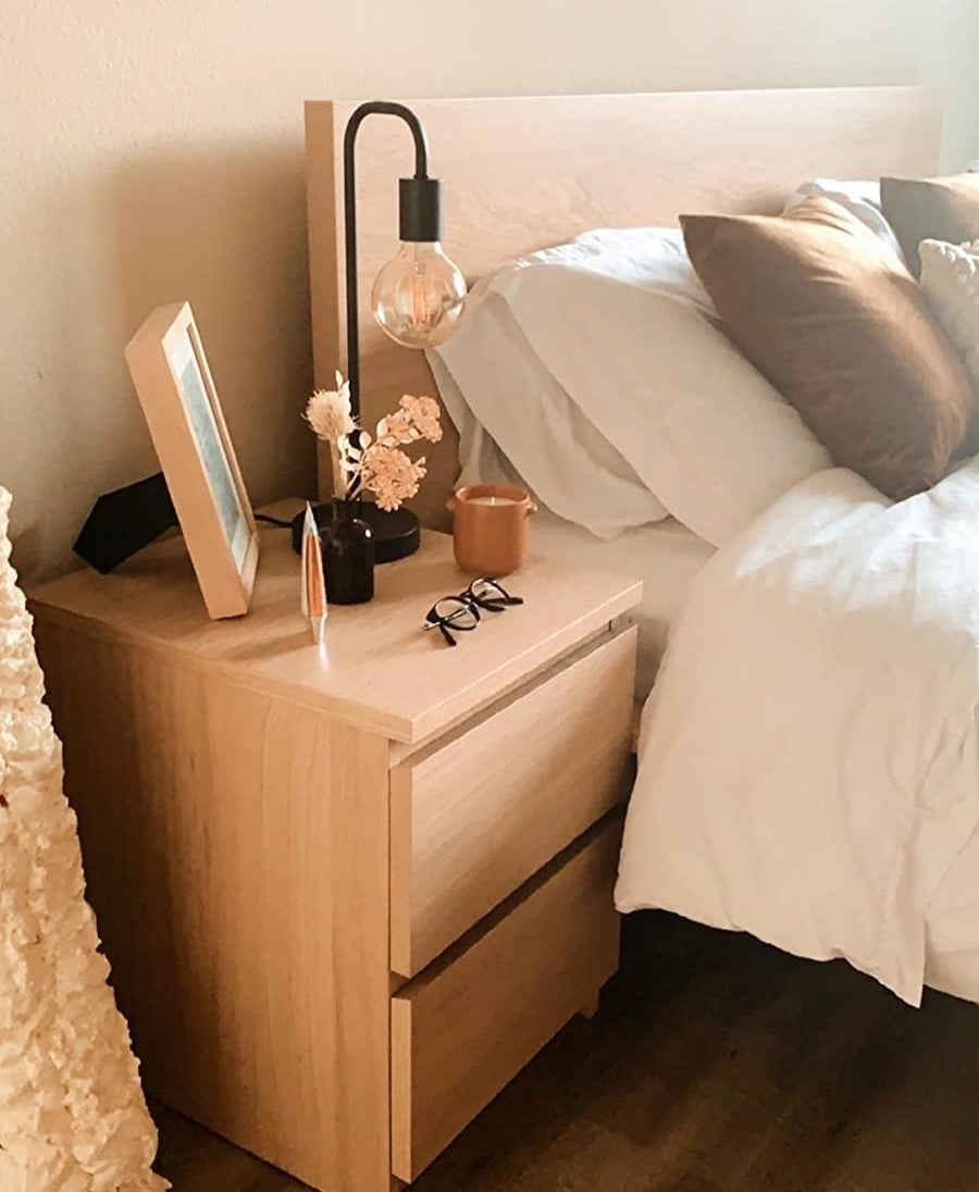 Reviewer pic of the black table lamp with large exposed lightbulb sitting on a bedside table