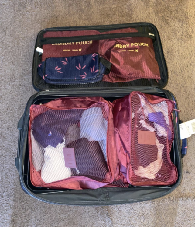 a reviewer&#x27;s photo of the packing cubes filled with clothing in a suitcase