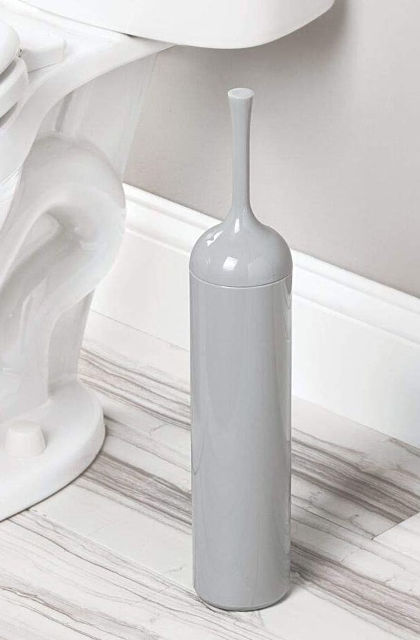 Sleek grey toilet bowl brush holder next to a toilet
