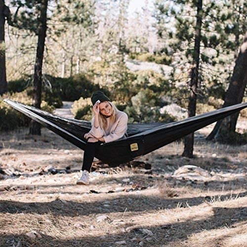 Model in a black hammock supported by two trees 