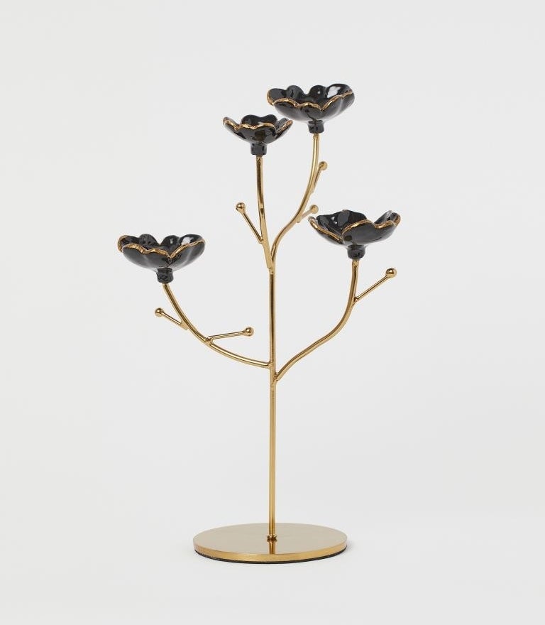 The gold jewelry holder with four stems with black and gold flower cups at the end