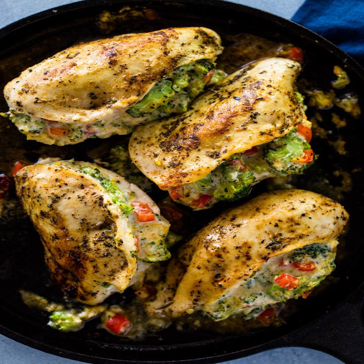 Four broccoli and cheese stuffed chicken breasts in a skillet.