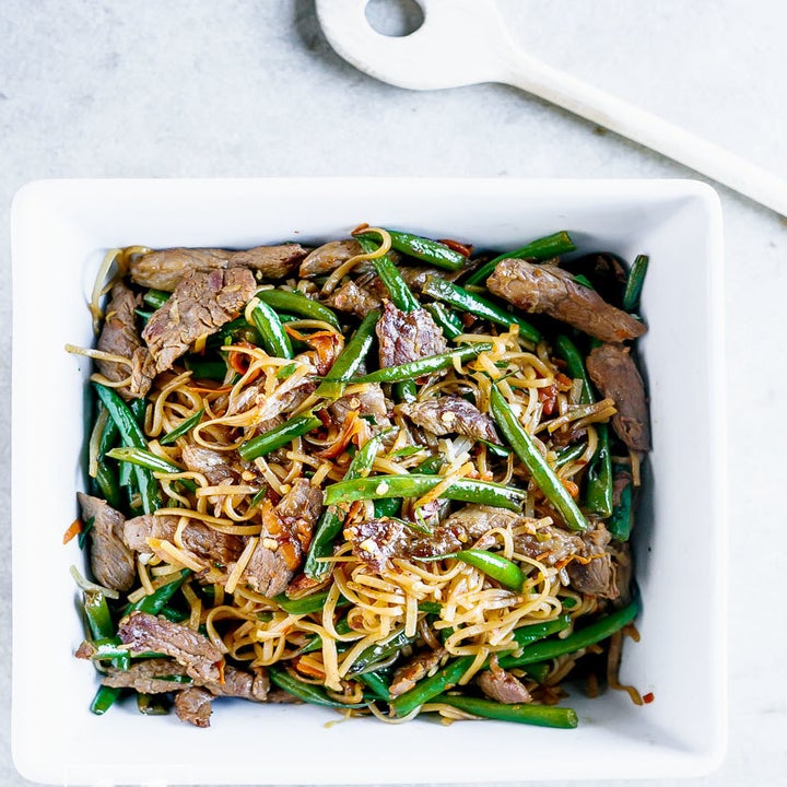 Beef and vegetable lo mein in a white bowl.
