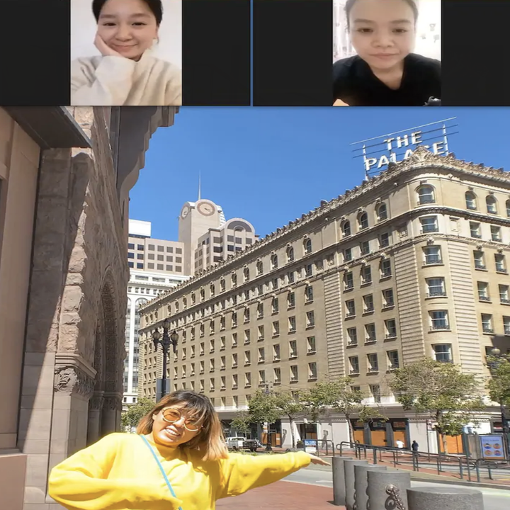 Two video chat tiles above a shared screen of a woman posing in front of a large building in San Francisco as she points to it