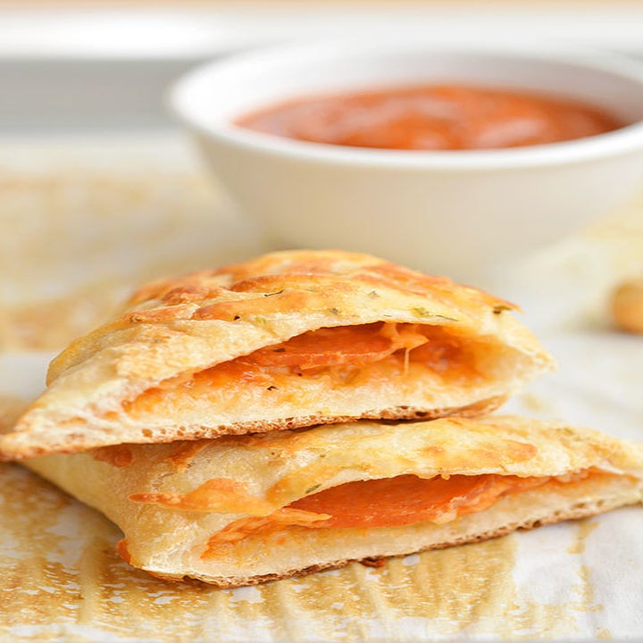 A pizza pocket sliced in half revealing a cheesy, pepperoni-filled interior.