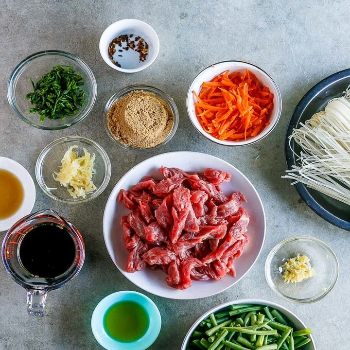 Lo Mein ingredients on a countertop including beef, noodles, green beans, carrots, scallions, soy sauce, garlic, and more.